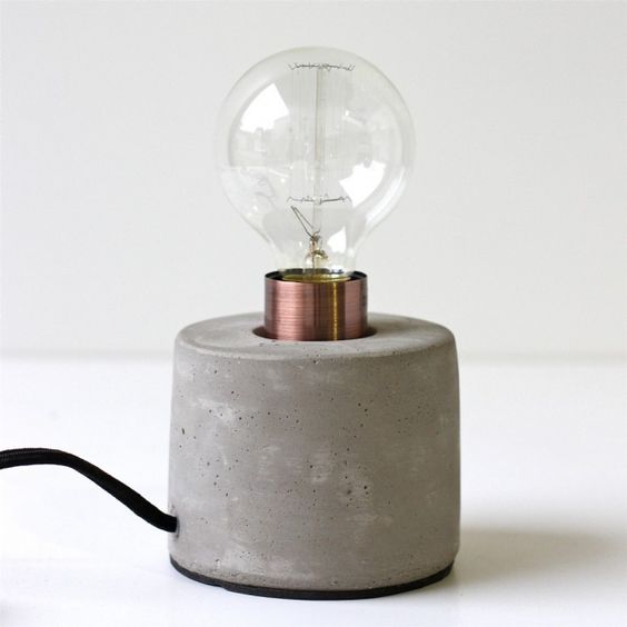 a table lamp with a concrete base and a bulb looks simple and laconic