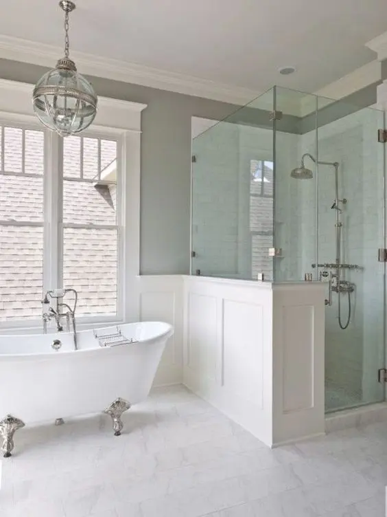 Vintage inspired bathroom in neutral colors with a white clawfoot bathtub on silver legs
