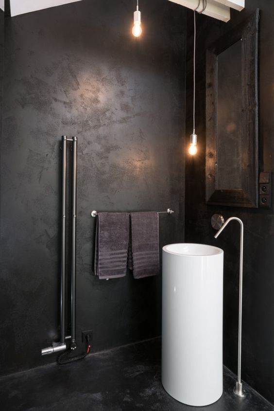 an industrial bathroom with a white free-standing sink that pops up