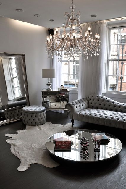 A silver grey living room with a large crystal chandelier with candle inspired bulbs