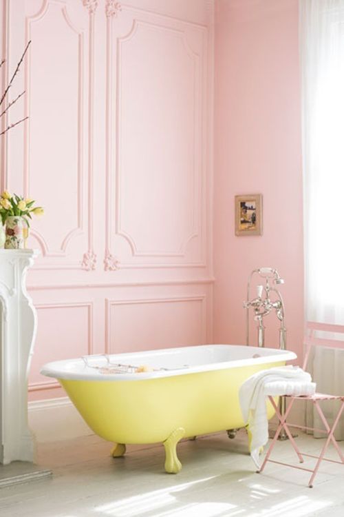 a fun sunny yellow clawfoot bathtub in a pink bathroom