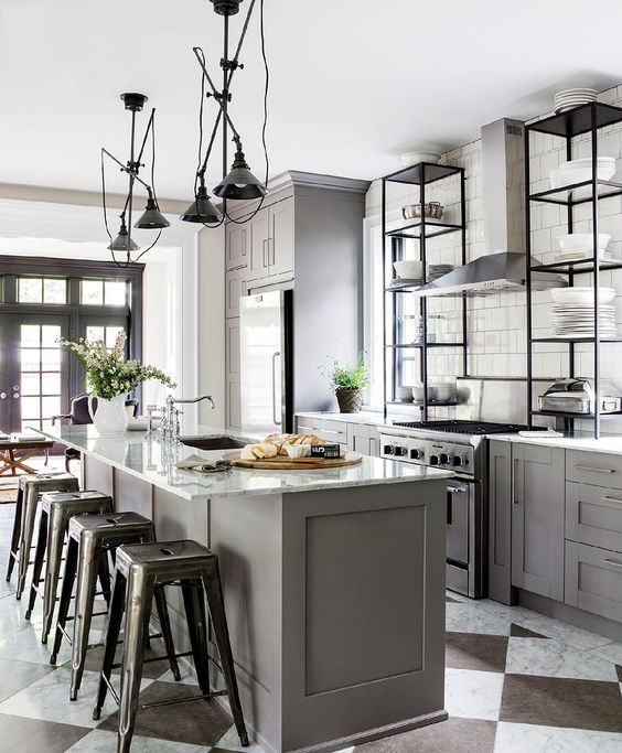 a grey kitchen island with a white marble countertop and industrial stools