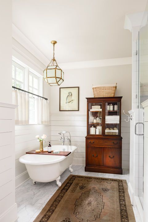 elegant vintage bathroom with a clawfoot tub, a wooden cabinet and a carpet