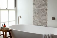 16 stone tiles and a wooden stool create a textural look and a large bathtub makes you relax