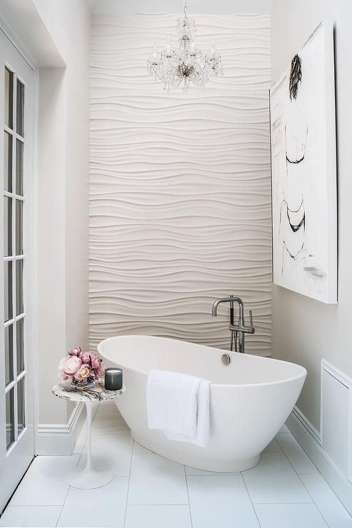 a glam bathroom with a textural wall and a small freestanding tub
