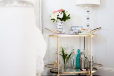 18 a bar cart as a nightstand with gilded accents is a very functional piece