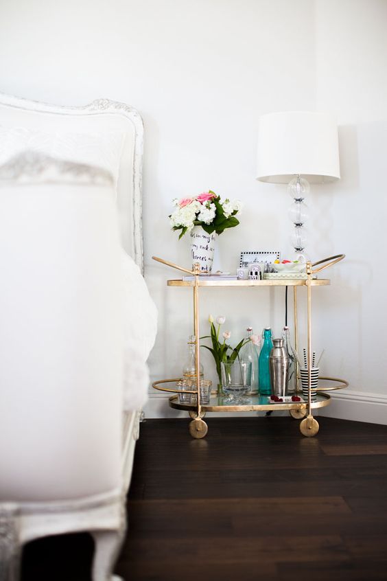 a bar cart as a nightstand with gilded accents is a very functional piece