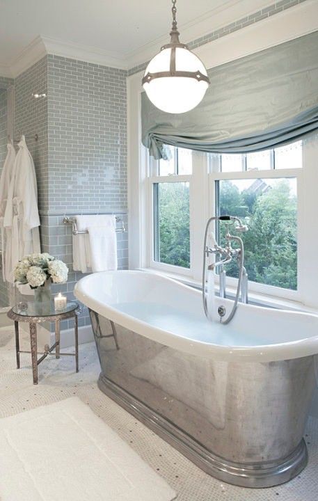 vintage-inspired bathroom with a metal-clad bathtub next to the window