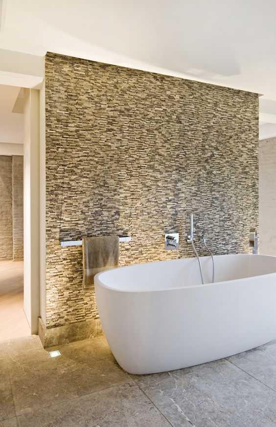 a stone accent wall and a white tub in front of it that stands out