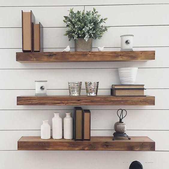 thick reclaimed wood floating shelves in front of a white plank wall