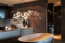 23 a moody bathroom with a dark textural stone bathtub as a focal point