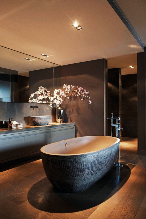 a moody bathroom with a dark textural stone bathtub as a focal point
