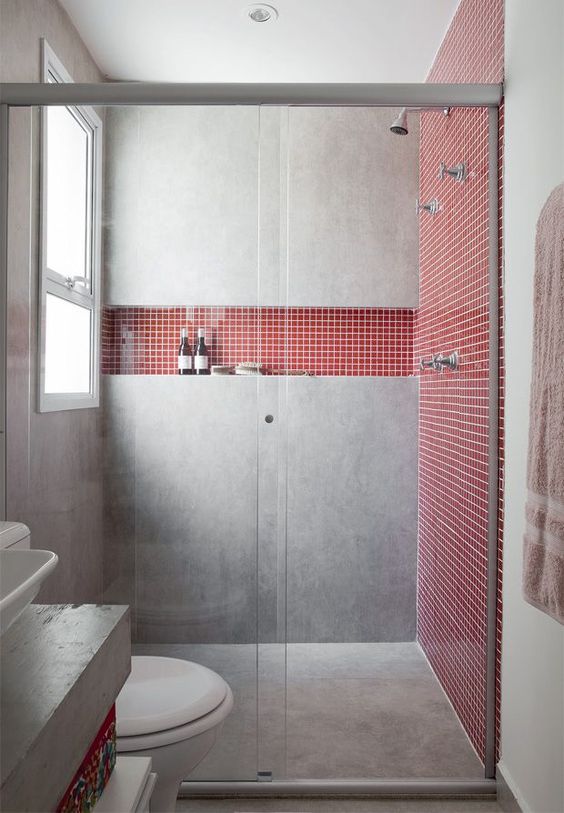 a concrete shower with coral tile inserts looks feminine yet very modern