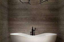 31 a wood clad bathroom with an eye-catchy tub and a gorgeous chandelier