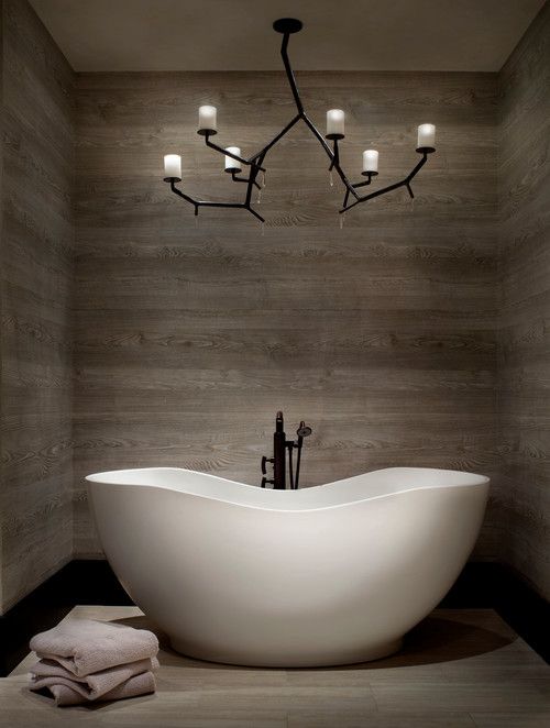 A wood clad bathroom with an eye catchy tub and a gorgeous chandelier