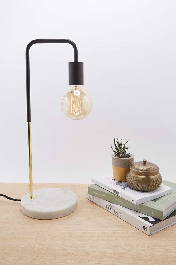 an industrial lamp with a marble base, a brass touch and black elements and a bulb