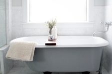 33 a grey clawfoot bathtub with black legs looks pretty modern
