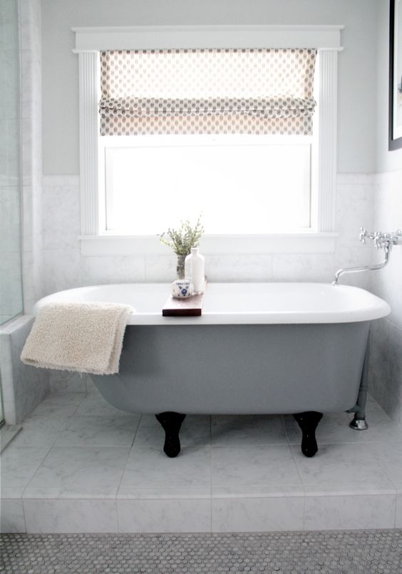 a grey clawfoot bathtub with black legs looks pretty modern