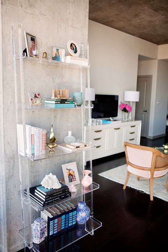 ladder-style lucite shelving unit disappears next to the concrete wall