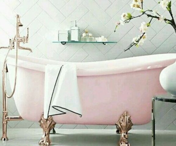 a pink slip freestanding bathtub with rose gold legs and bathtub filler for a feminine space