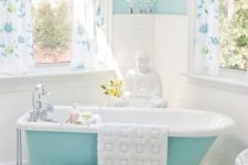 40 aqua-colored clawfoot tub in a girlish bathroom with a chandelier and floral curtains