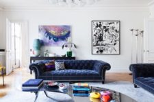 01 The living room is dotted with colors – navy velvet furniture and some bold artworks and a mirror kidney-shaped table catches an eye