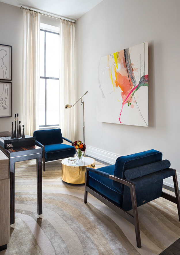 There's a bold abstract artwork on one of the walls and a couple of navy velvet chairs to enjoy it