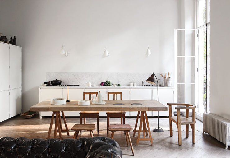 The kitchen and dining space are united in one, with white cabinets and light colored wooden dining set