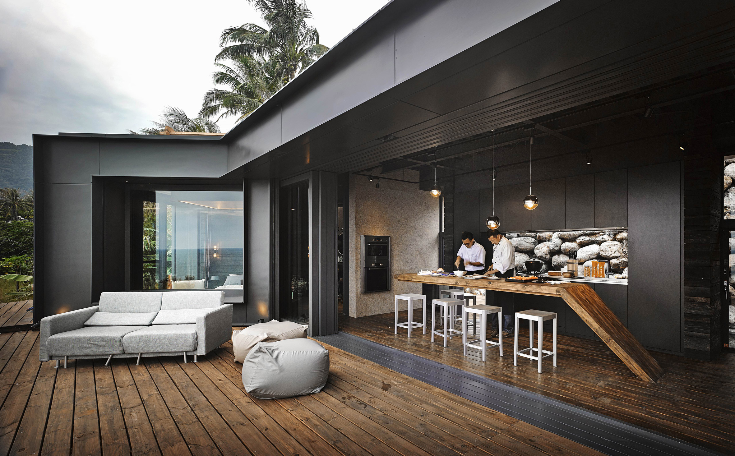 The kitchen is minimalist and dark and it can be opened to the outdoors easily
