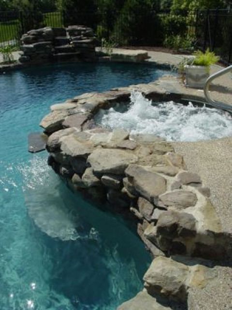 A hot tub covered with riverstone to separate it from a kidney shaped pool