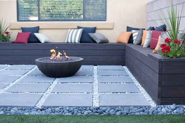 dark pallet bench with storage and a fire pit on a stone tile deck