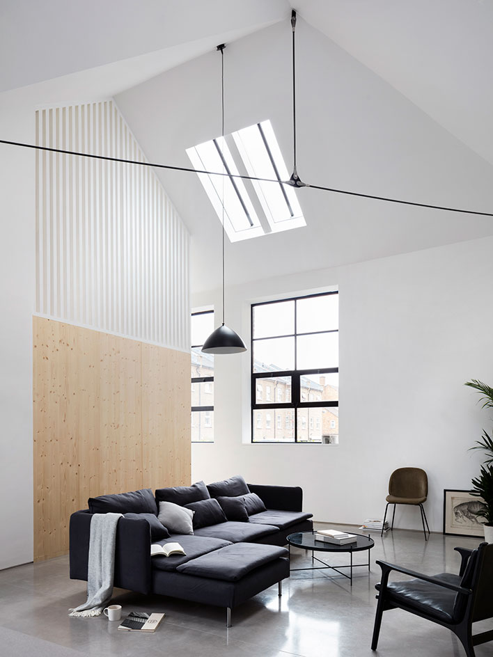 The living room is full of light, with a large corner sofa and pendant lamps that highlight the double height ceilings