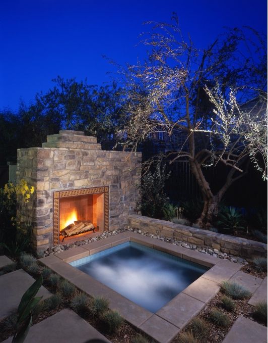 sunken jacuzzi clad with stone and with a fireplace in front of it for more comfort