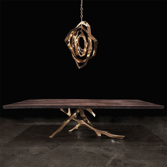 a dark stained table with bronze branch legs and a matching pendant