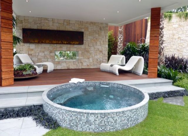 a round jacuzzi clad with small blue tiles in front of a deck