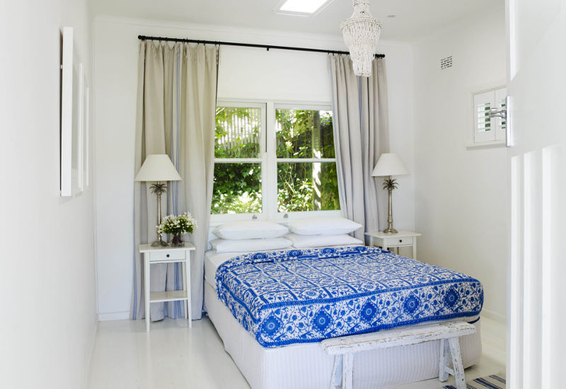 The second bedroom is all white with a bold patterned bedspread