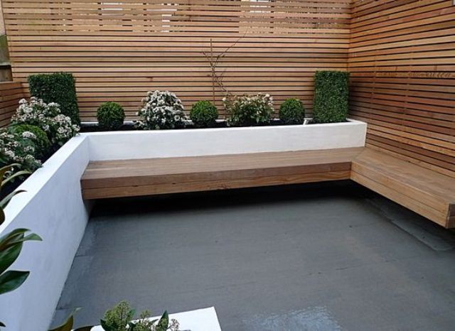A cozy wind sheltered area with a bench and a white modern planter