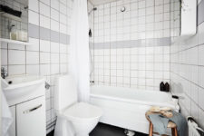 14 The bathroom is done in white and grey tiles, and a wooden stool adds texture