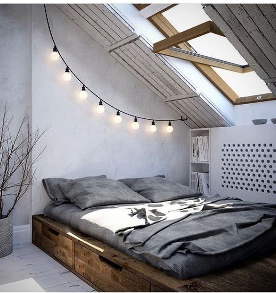 a reclaimed stained wooden bed with drawers gives the attic bedroom a barn feel