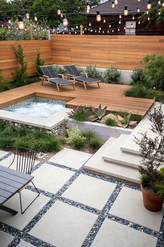a wood deck with loungers and a jacuzzi surrounded with succulents