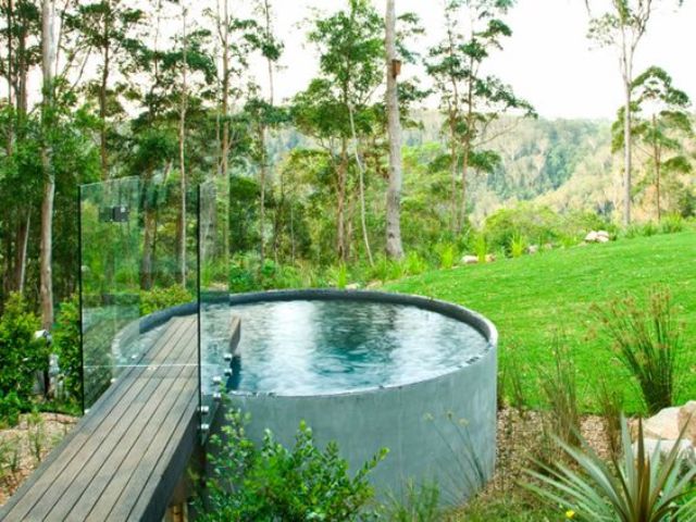 A free standing jacuzzi with a wooden bridge and glass rails