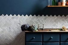 24 navy cabinets and a wall, marble tiles clad in a chevron pattern