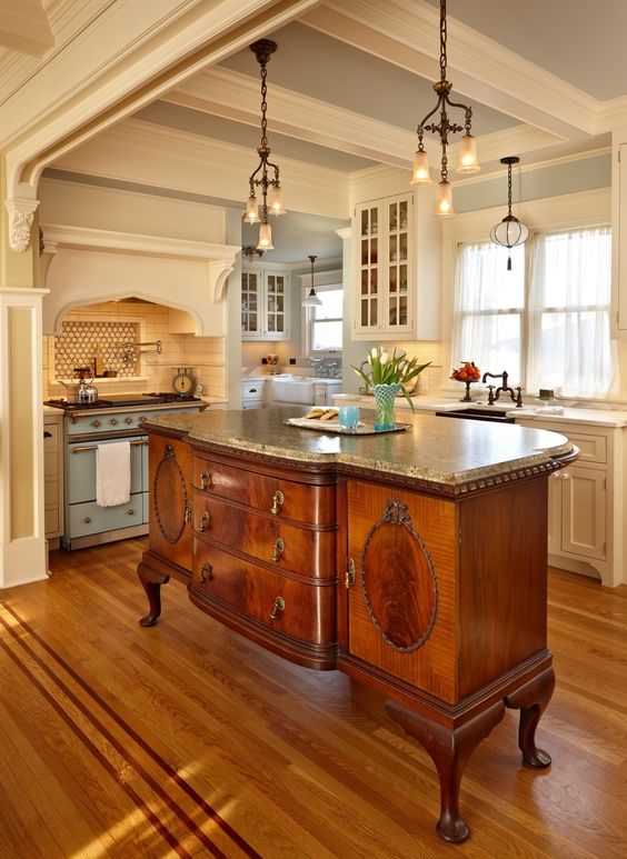 an antique French cabinet with a granite counter used as a kitchen island