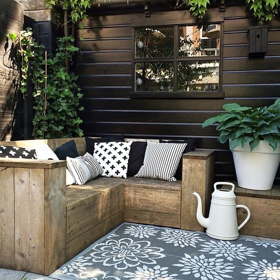 small rustic L-shaped wooden bench with graphic pillows for a Nordic terrace