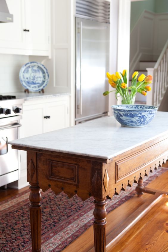 a vintage rustic table with carved legs and a marble counter