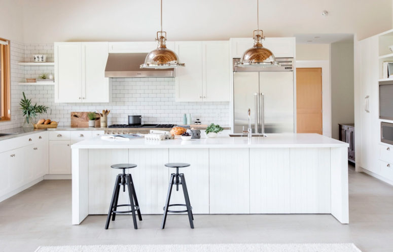 The kitchen features white cabinets and tiles, a large kitchen island and stainless steel countertops