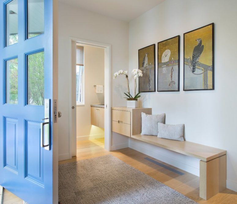 The entryway fetures artworks with light-colored wooden furniture, modern and chic
