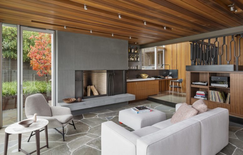 The walls are covered with different types of wood, the floor is done of stone and the fireplace is covered with concrete for a masculine feel