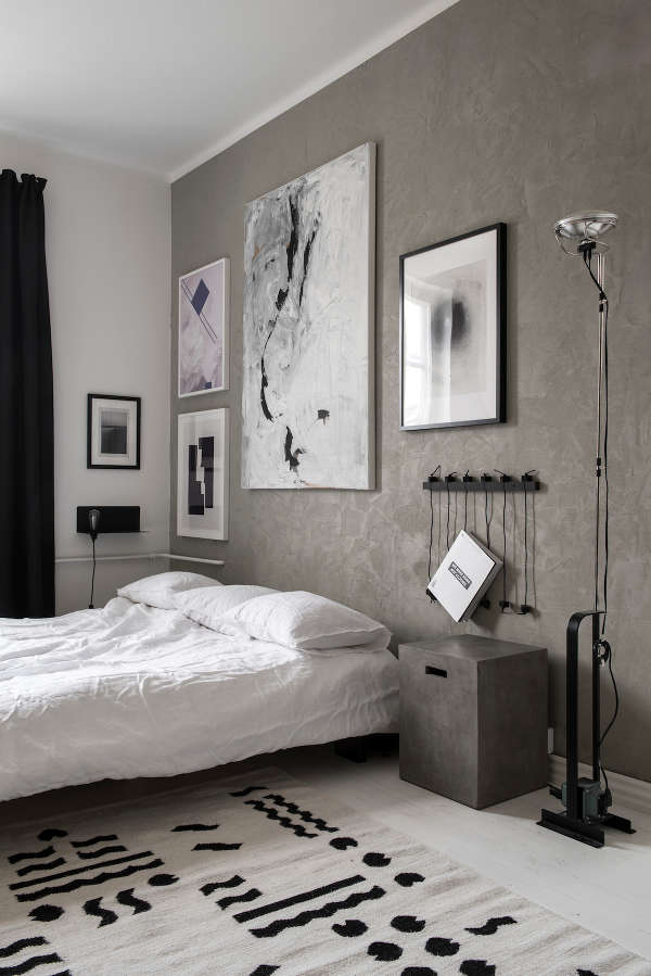The bedroom has a grey accent wall and matching bedside tables, all the rest is laconic black and white
