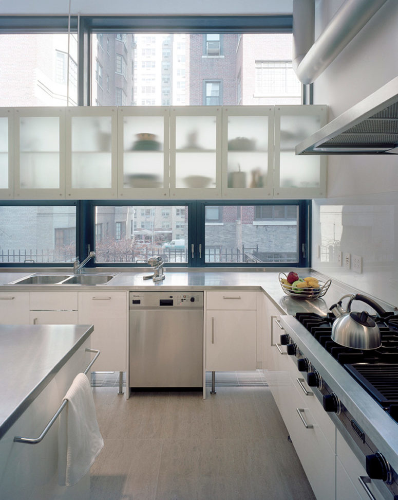 The kitchen is light-filled and spacious, with silver and white cabinets and steel surfaces